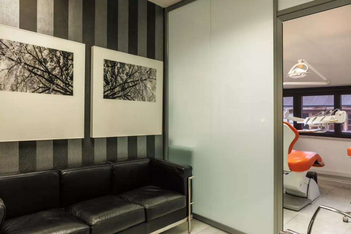 Sala de espera de la clínica junto a una puerta de una sala con un sillón de dentista