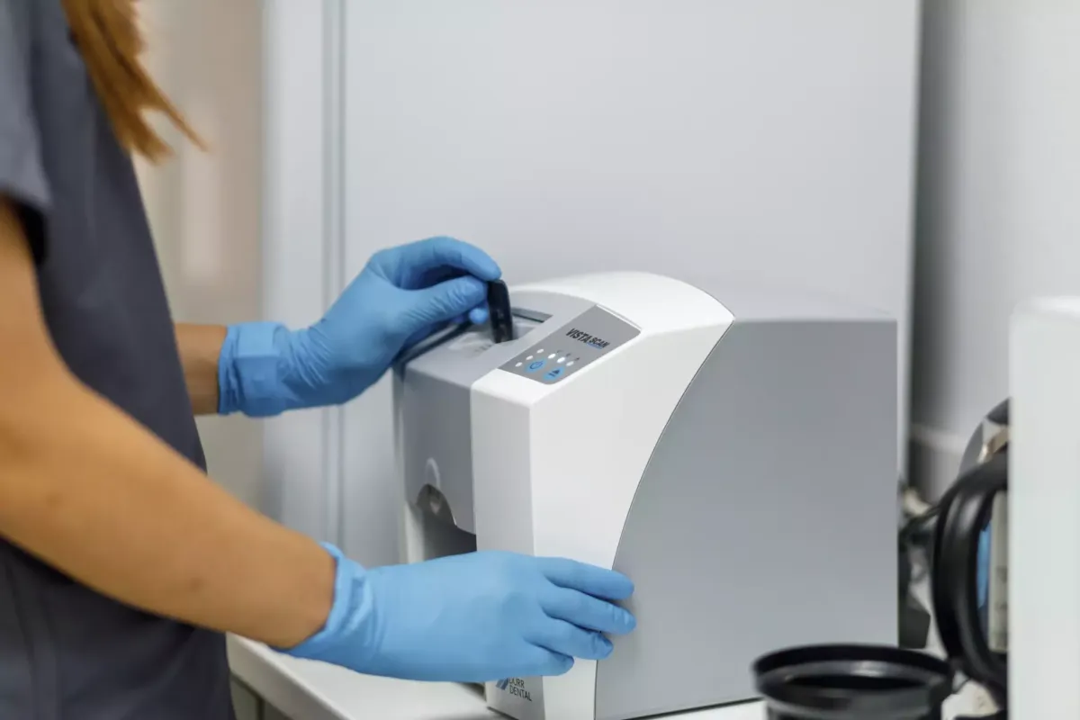 Manos con guantes de látex mientras se manipula una máquina